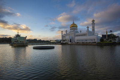 View of omar ali saifuddien at waterfront against cloudy sky