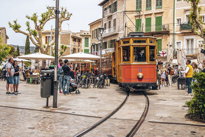 Tourists looking at famous tram moving on rail tracks against buildings in city