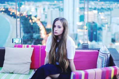 Beautiful woman sitting on sofa against window