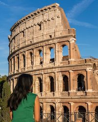 Rear view of woman leaning against historical building