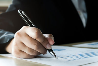 Close-up of hand holding paper on table