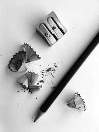 High angle view of pencil with shavings and sharpener on white background