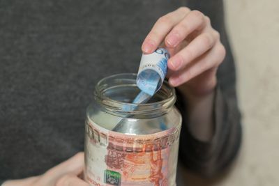 Midsection of woman removing paper currency from jar