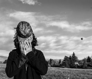 People on grassy field against cloudy sky