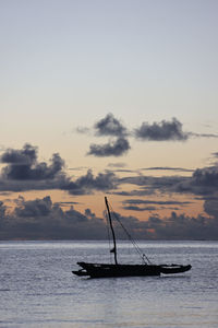 Silhouette sailboat in sea against sky during sunset