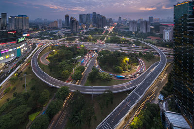 High angle view of illuminated street amidst buildings against sky