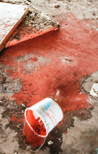 High angle view of abandoned red paint on concrete wall