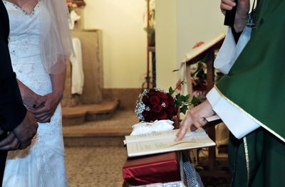 Midsection of priest with bride and groom in church