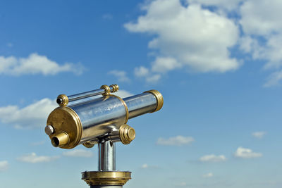 Low angle view of coin-operated binoculars against blue sky