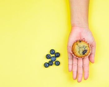 Midsection of person holding fruit against yellow background