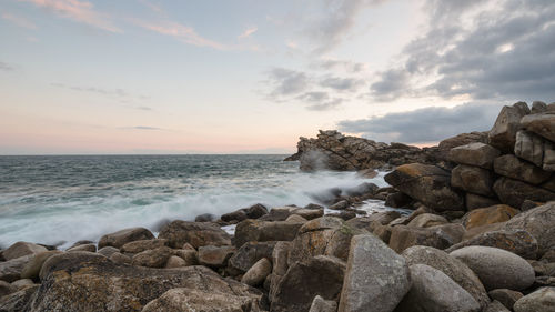 Scenic view of rocky beach against sky during sunset