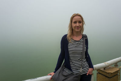 Portrait of smiling woman against sea during foggy weather