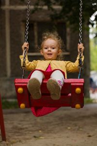 Portrait of girl sitting on swing at playground