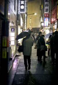 People walking on wet street at night