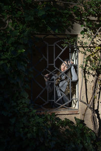 View of a woman leaning behind a window with a nice lighting in the nature