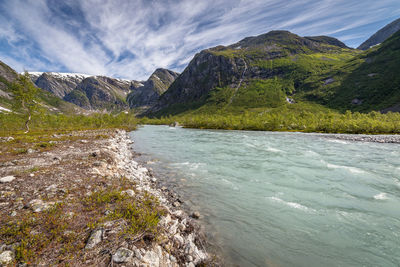 Scenic view of sea by mountains against sky