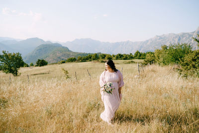 Rear view of woman standing on field against sky