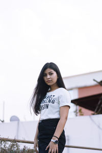 Portrait of a beautiful young woman standing against clear sky