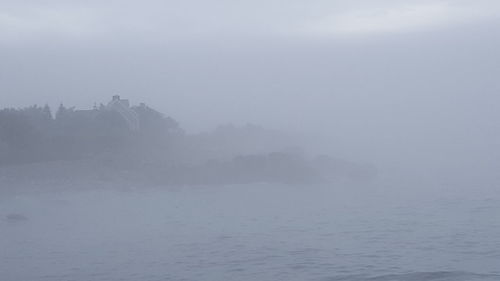 Scenic view of mountains in foggy weather against sky