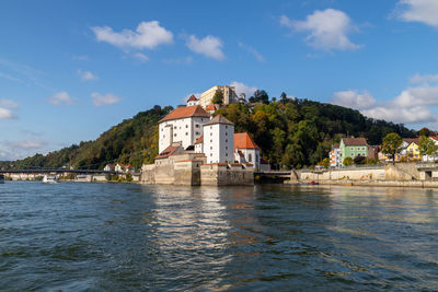 River by buildings in city against sky