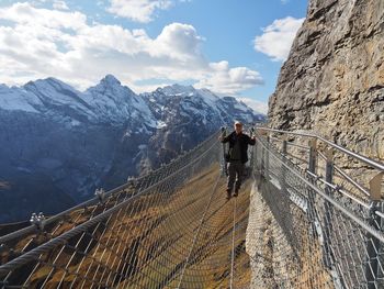 Portrait of man on footbridge against mountains