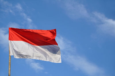 Low angle view of indonesian flag against blue sky