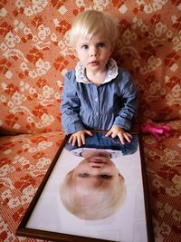 Portrait of cute baby sitting with mirror at home