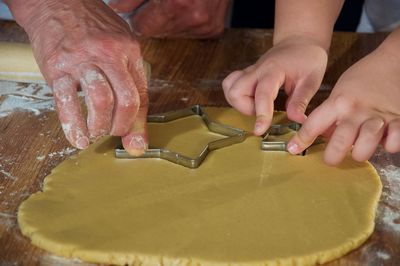 Cropped hands of people preparing cookies on table