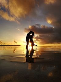 Silhouette men standing on beach against sky during sunset