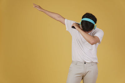 Rear view of man standing against yellow wall