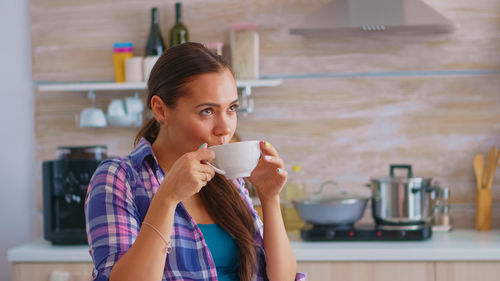 Portrait of young woman drinking milk at home