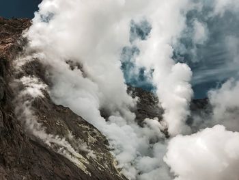 Smoke emitting from volcanic mountain against sky