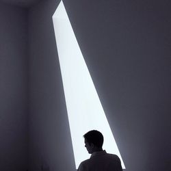 Rear view of a young man looking away against wall