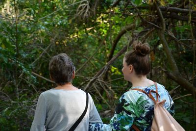 Rear view of grandmother and daughter walking in forest