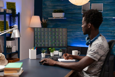 Side view of man using laptop at table