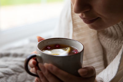 Woman drinking hot tea while resting at home in morning, sitting by window. autumn time, flu season.