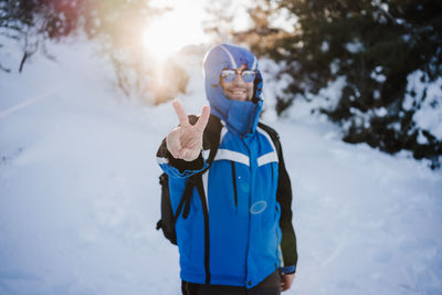 Portrait of man gesturing while standing on snow covered land during winter