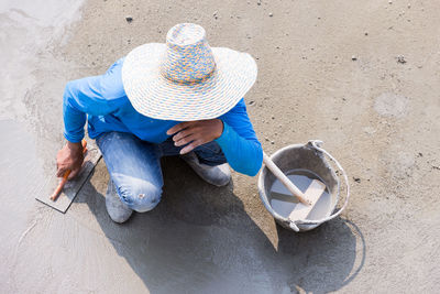 High angle view of worker leveling cement on footpath