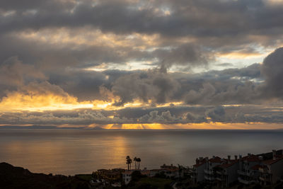 Scenic view of sea and buildings against dramatic sky