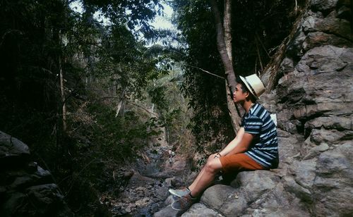 Woman standing on tree trunk in forest