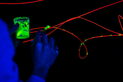 Close-up of hand holding illuminated lights against black background