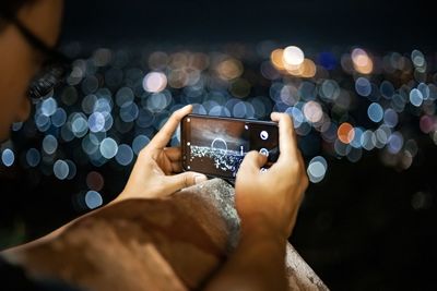 Midsection of man using mobile phone at night