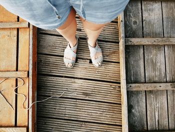 Low section of woman standing on wooden boardwalk