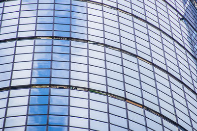 Low angle view of glass building against blue sky