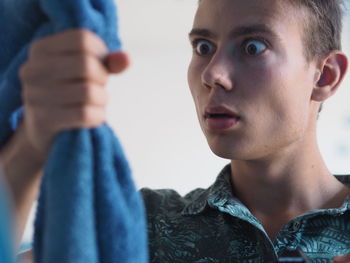 Surprise man holding towel against wall at home