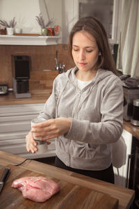 Beautiful woman preparing meat at kitchen