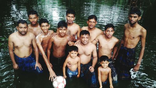 Portrait of friends with children standing in lake