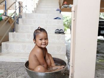 Portrait of shirtless girl sitting in container