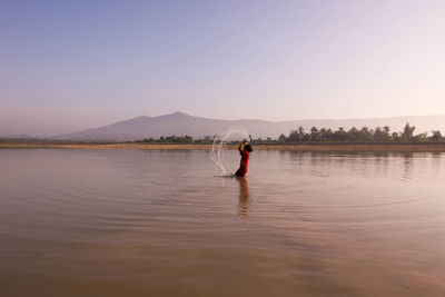 Rear view of man on lake against sky