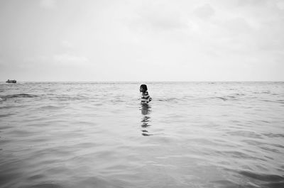 Rear view of man in sea against sky